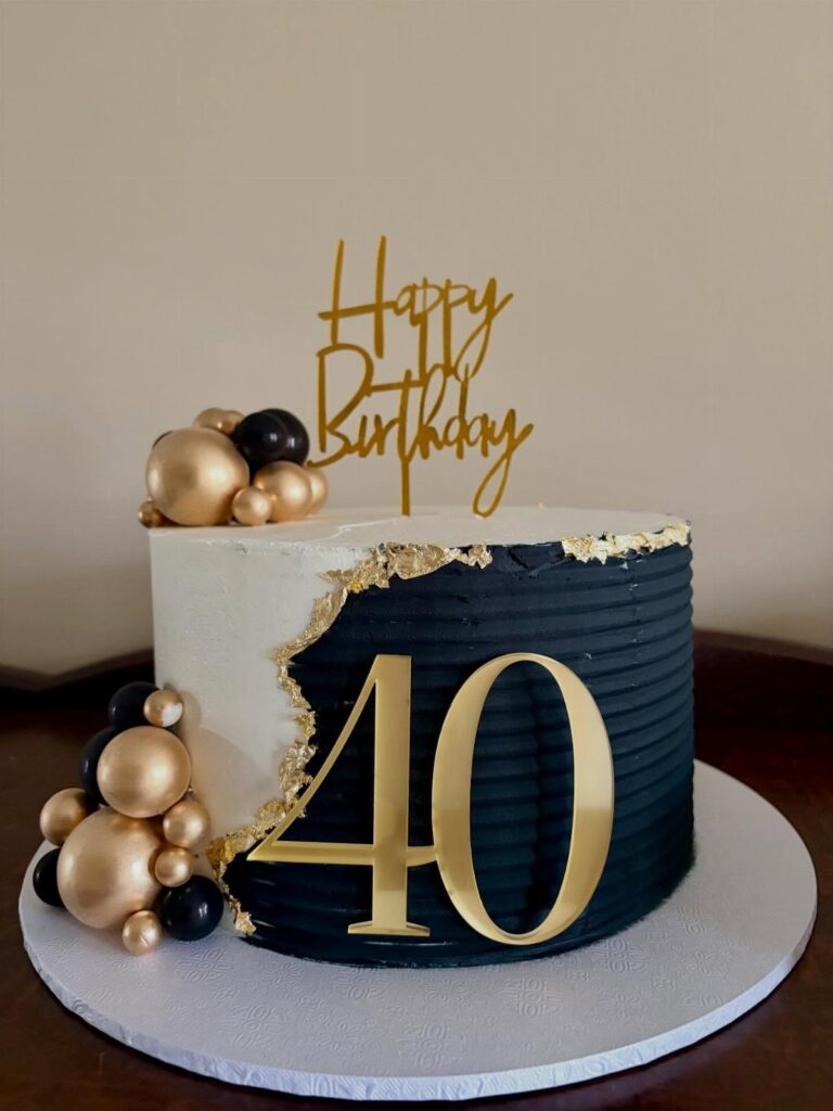 Black and white birthday cake with gold 40 topper and spherical decorations