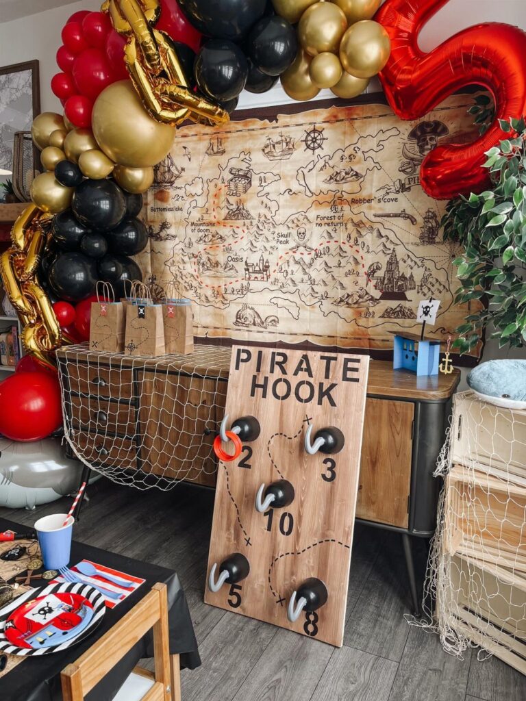 Pirate party decorations with a balloon arch, treasure map, and pirate hook game.