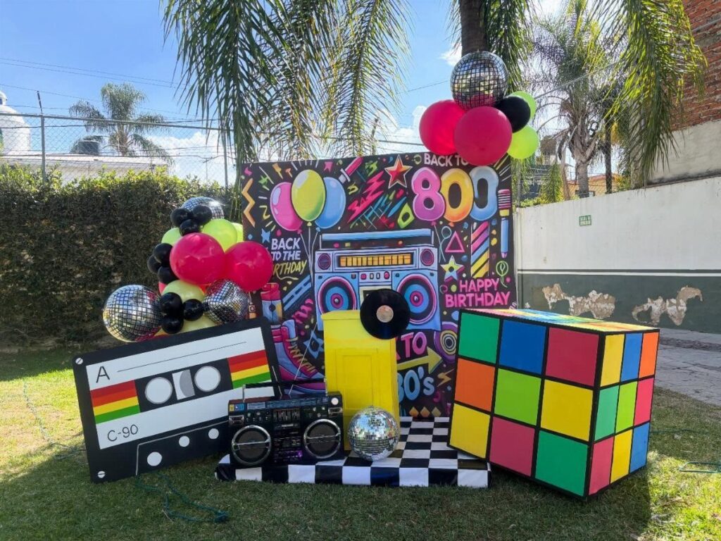 80s party decorations featuring a giant Rubik's cube, cassette tape, and colorful balloons.