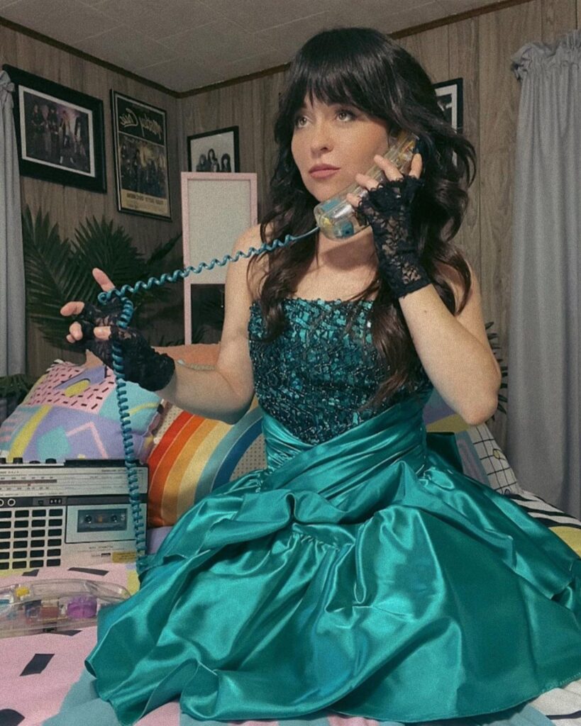 Woman in a teal sequined prom dress and lace gloves using a vintage phone.