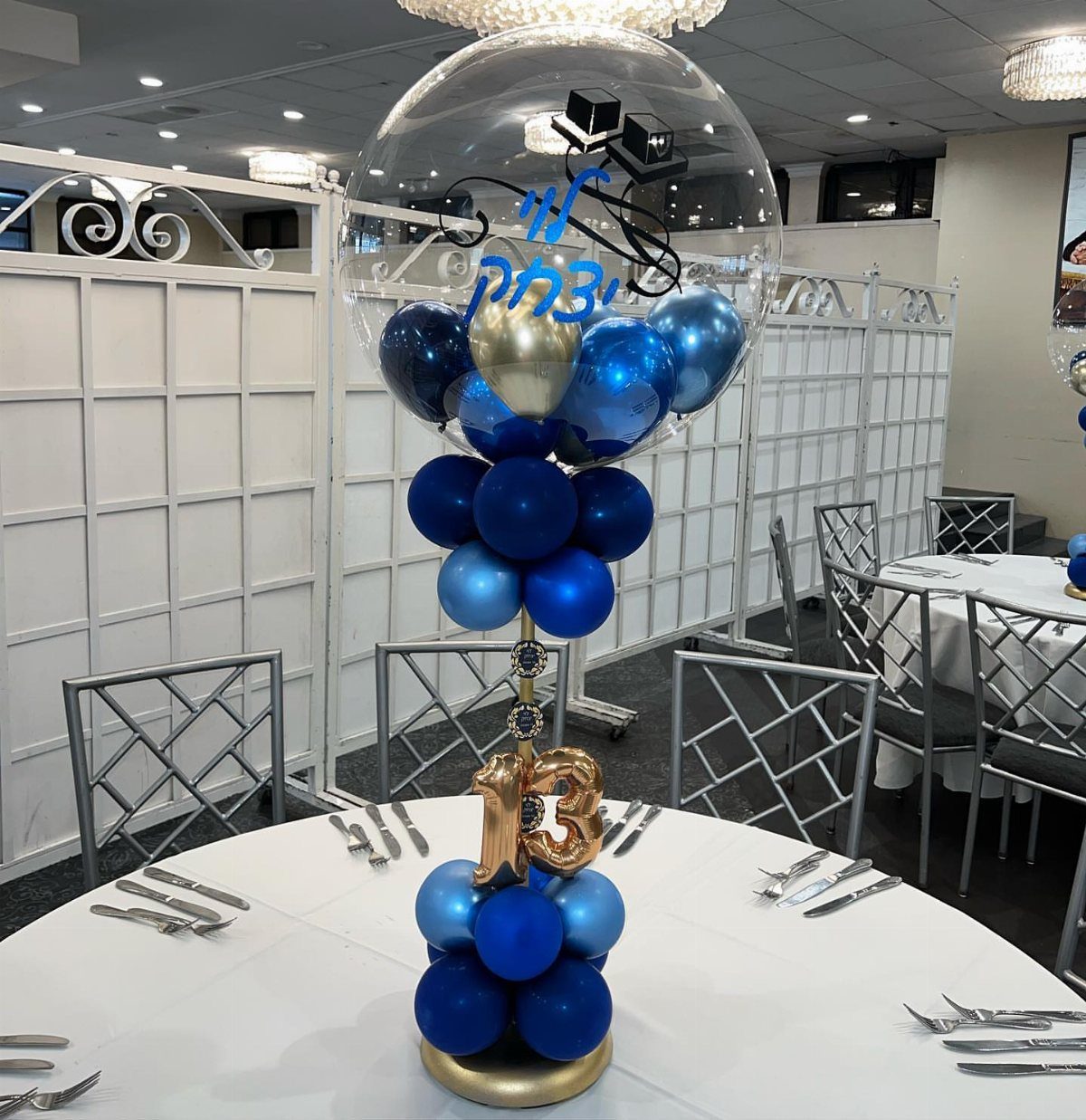 Balloon centerpiece with blue and gold balloons and a gold number 13.