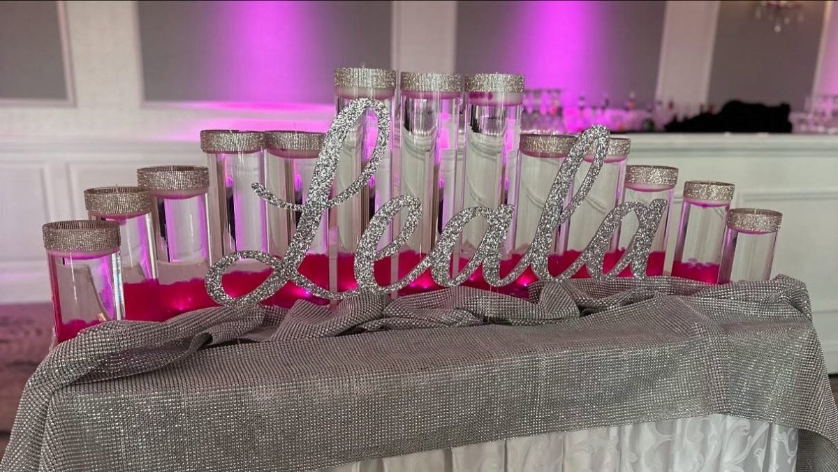 Floating candles in pink water with a silver glittery name sign on a table