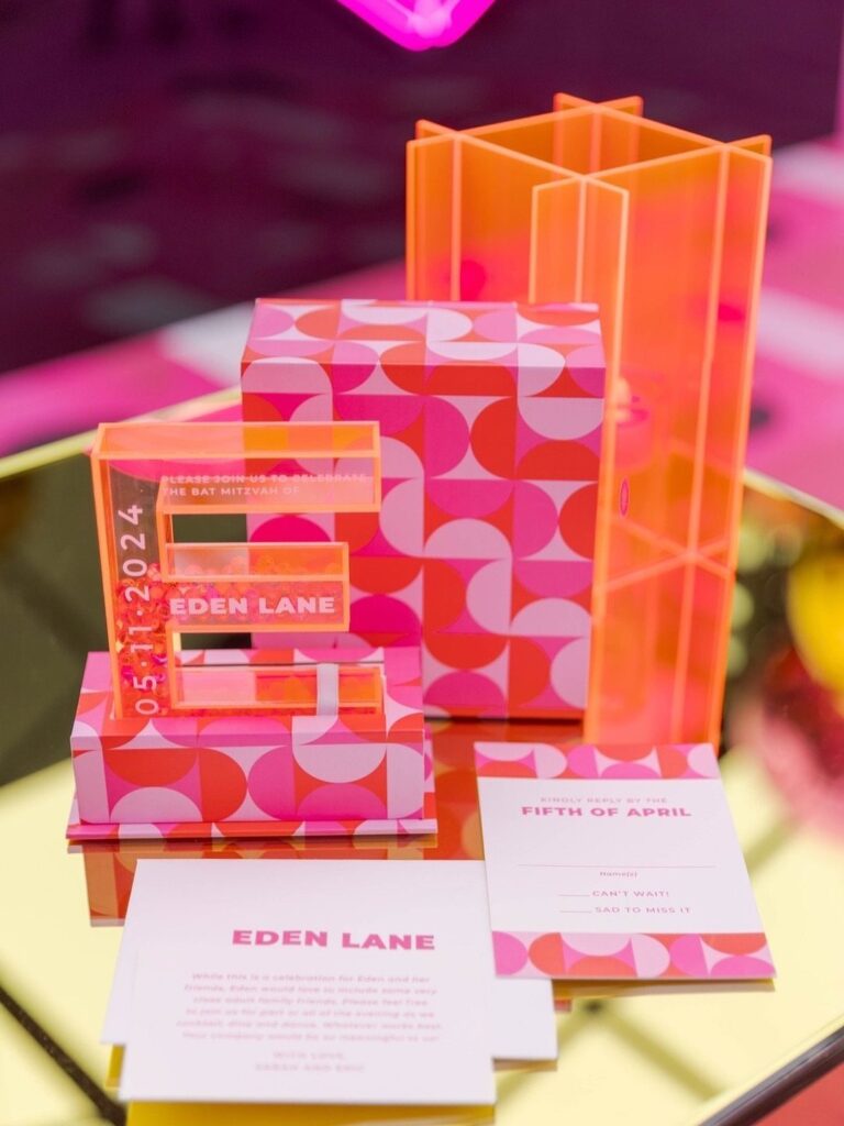 Pink and orange Bat Mitzvah invitation suite with acrylic letter E and patterned box.