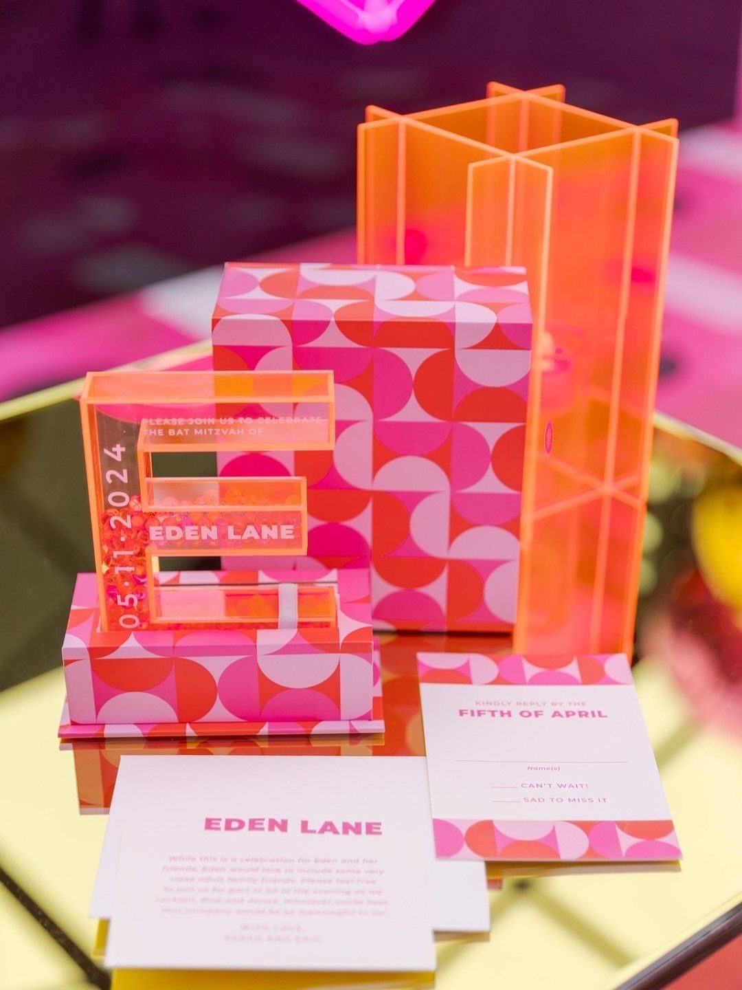 Pink and orange Bat Mitzvah invitation suite with acrylic letter E and patterned box.
