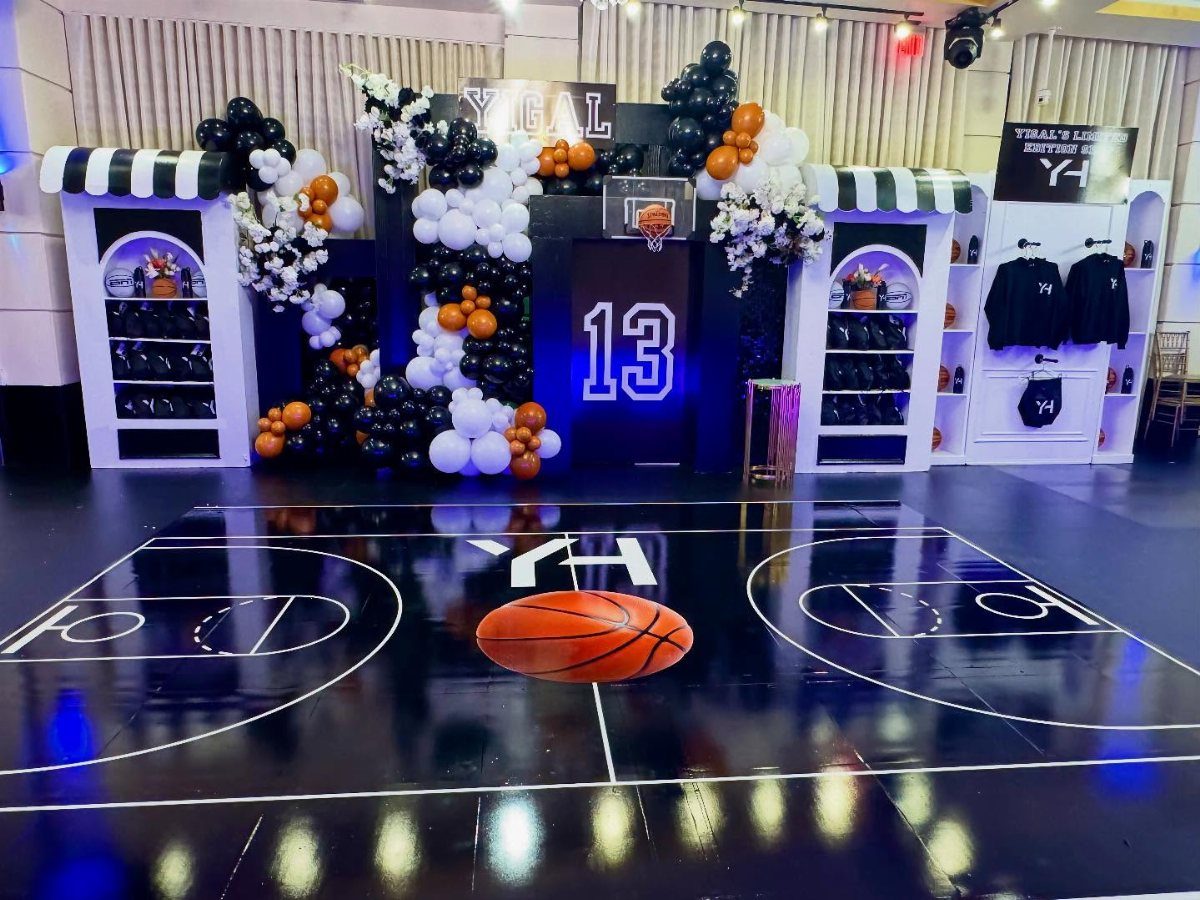 Basketball themed party decor with a court dance floor and orange and black balloons.