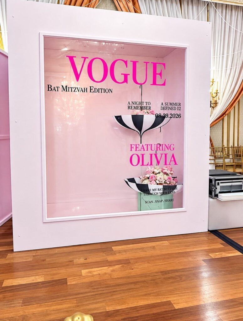 Vogue themed bat mitzvah photo booth with pink walls and floral accents