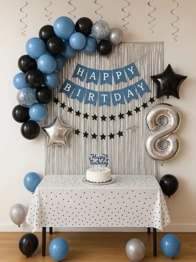 Birthday party decorations with blue and black balloons, banner, and cake on table.