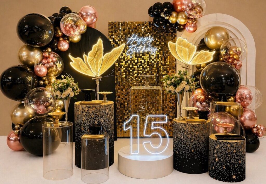 Black and gold party decorations with balloons, glittery pedestals, and a glowing number 15.