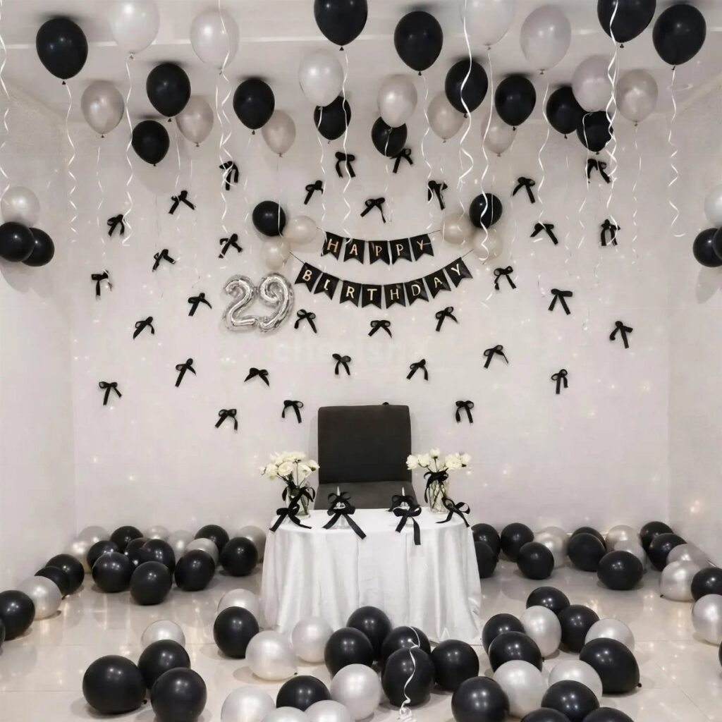 Black and white birthday party decorations with balloons, banner, and a decorated table.