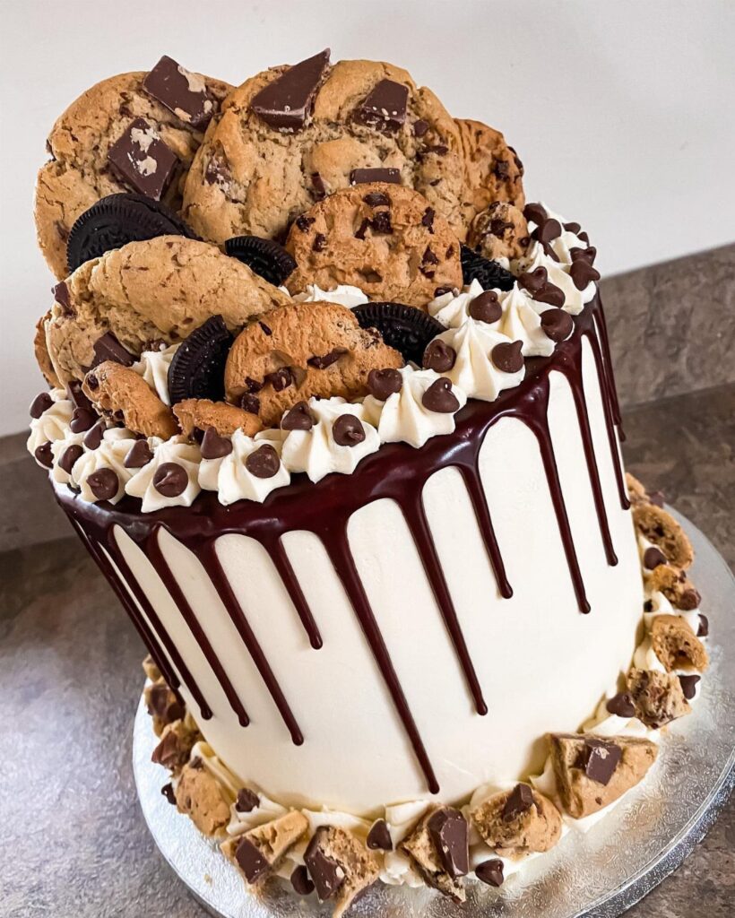 White frosted cake topped with chocolate chip and Oreo cookies and chocolate drip.