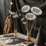 Halloween party decorations with ghost cutouts, BOO signs, and a witch hat on a table.