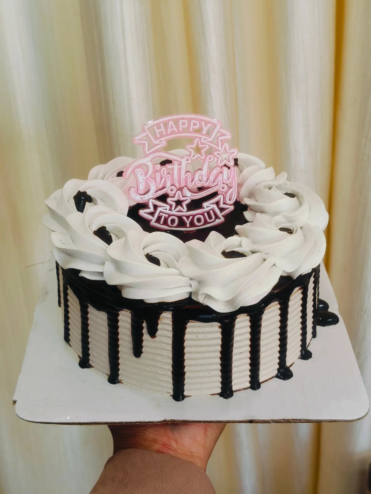 White frosted birthday cake with chocolate drip and pink Happy Birthday topper