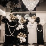 New Year's party decor with black, white, and gold balloons on checkered flooring.
