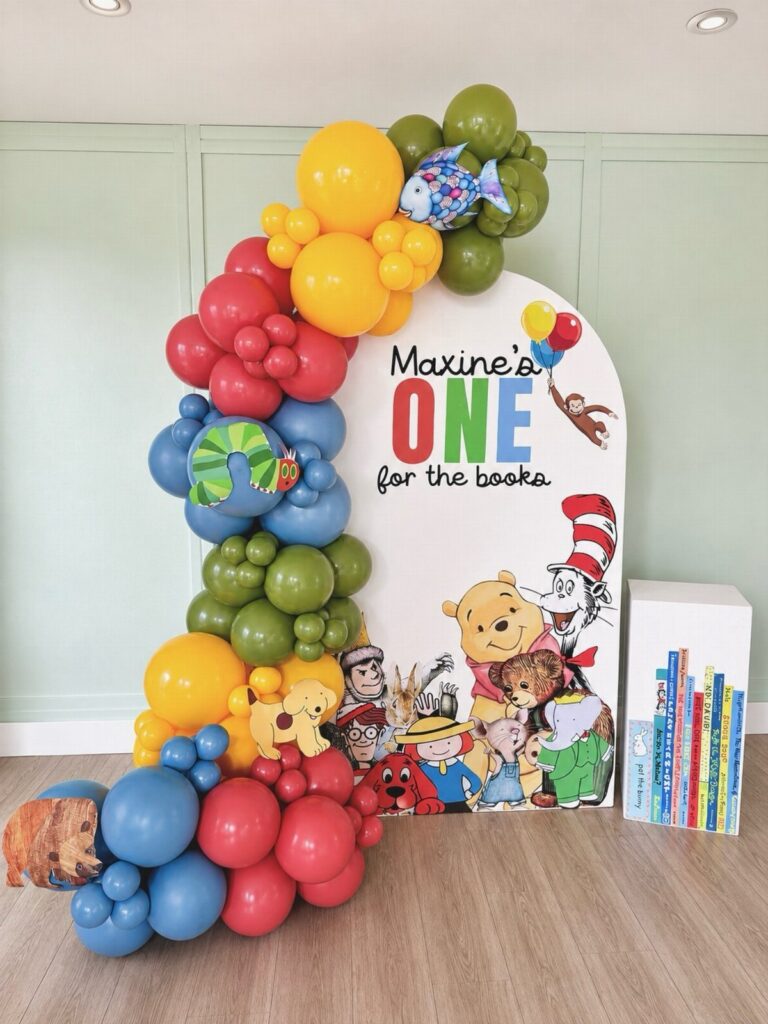 Birthday backdrop with colorful balloons and children's book characters for a first birthday.