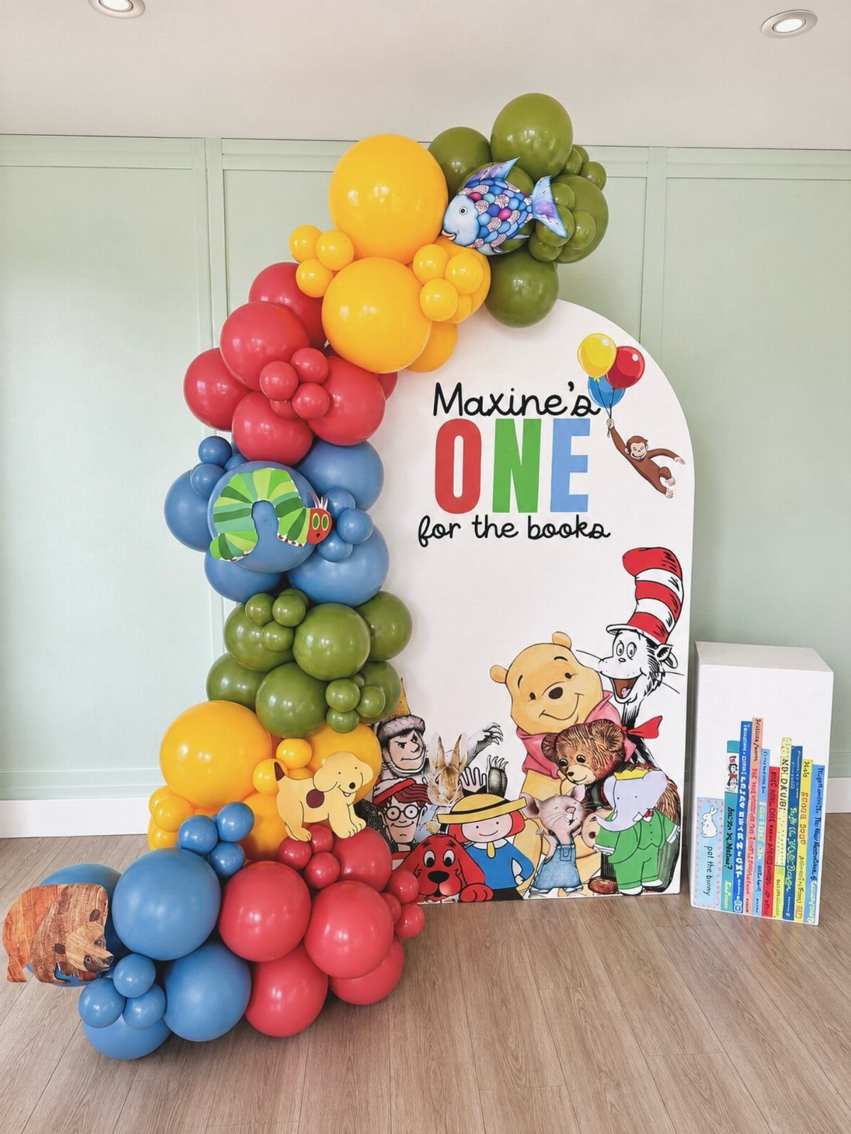 Birthday backdrop with colorful balloons and children's book characters for a first birthday.
