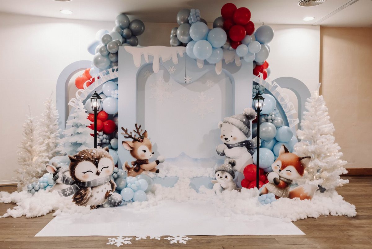 Winter party setup with blue balloons, white trees, and cute arctic animal figures.