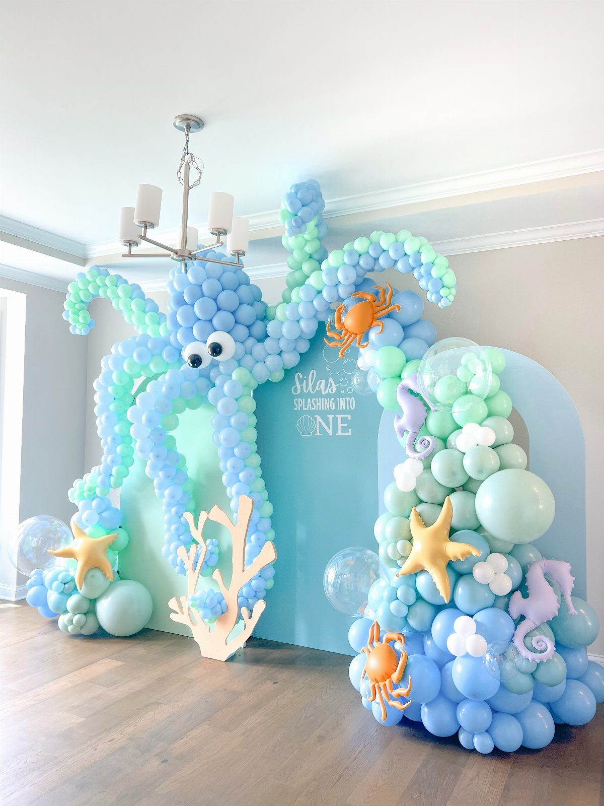 Balloon octopus installation with mint and blue balloons, starfish, and crabs for party.