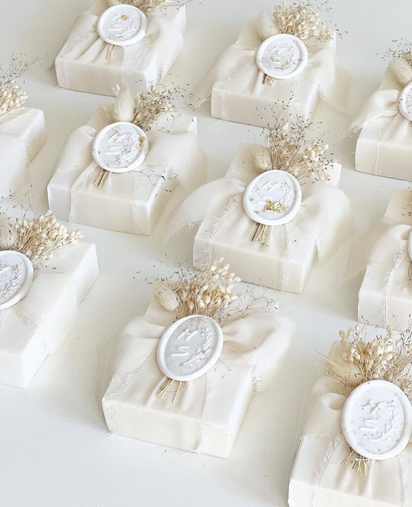 Wrapped white soap bars with wax seals and dried flowers as wedding favors.
